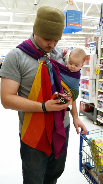 A father wearing a ring sling baby carrier.