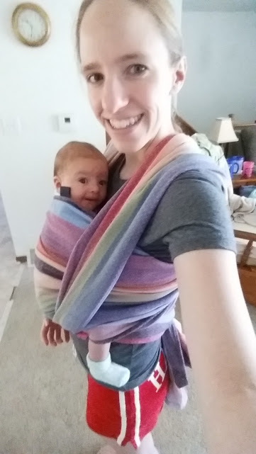 A mother wearing her baby in a woven baby wrap.